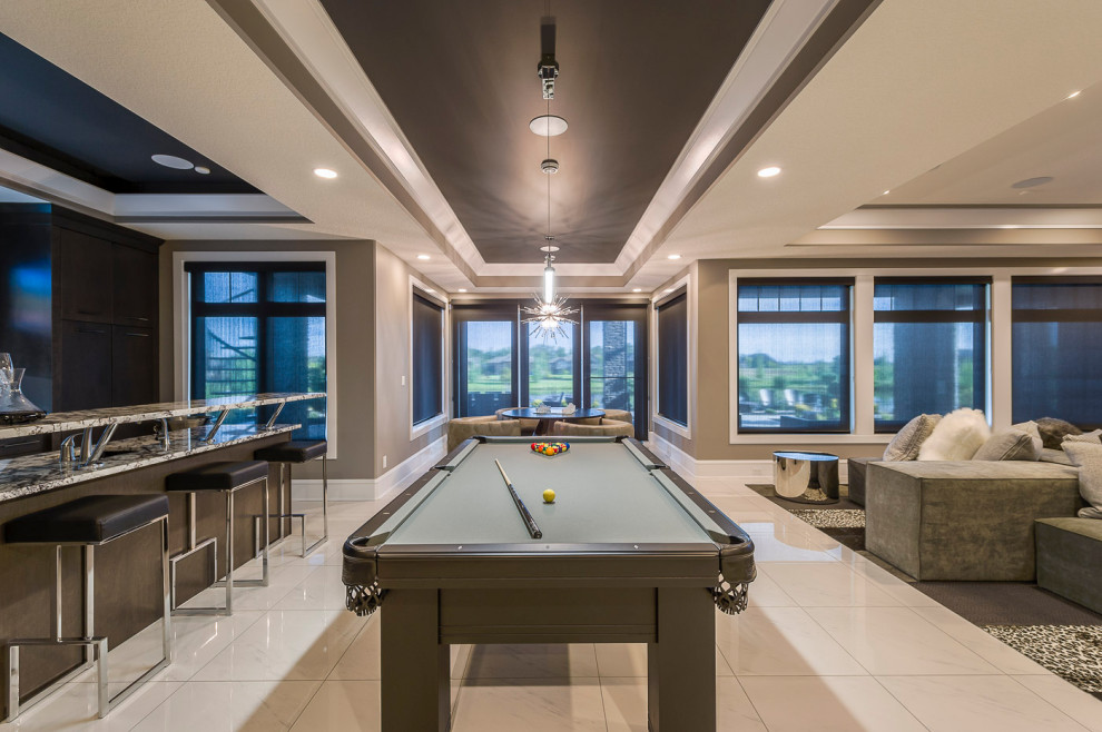 Example of a huge classic walk-out ceramic tile, white floor and coffered ceiling basement game room design in Edmonton with beige walls, a hanging fireplace and a stone fireplace