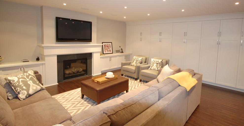 Example of a large transitional look-out dark wood floor basement design in Toronto with beige walls, a standard fireplace and a stone fireplace