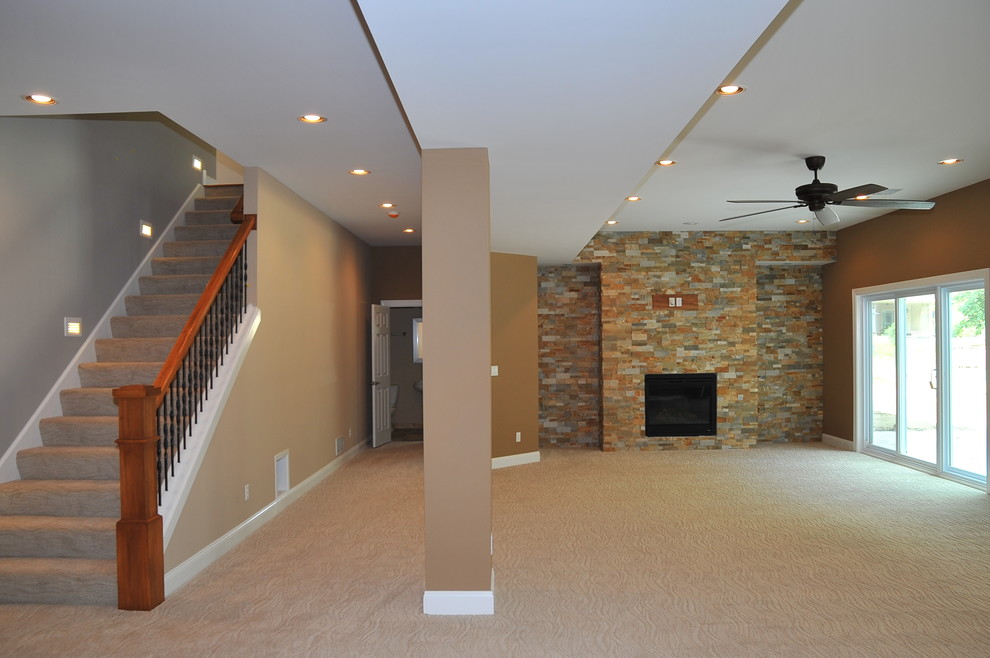Aménagement d'un grand sous-sol craftsman donnant sur l'extérieur avec un mur marron, moquette, une cheminée standard et un manteau de cheminée en pierre.