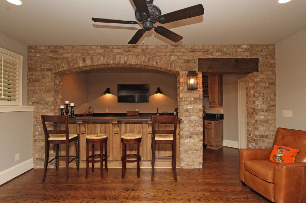 Modelo de sótano con ventanas clásico de tamaño medio sin chimenea con paredes grises, suelo de madera en tonos medios y suelo marrón