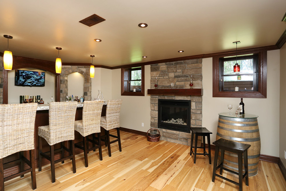 Basement - small craftsman look-out light wood floor basement idea in Toronto with beige walls, a standard fireplace and a stone fireplace