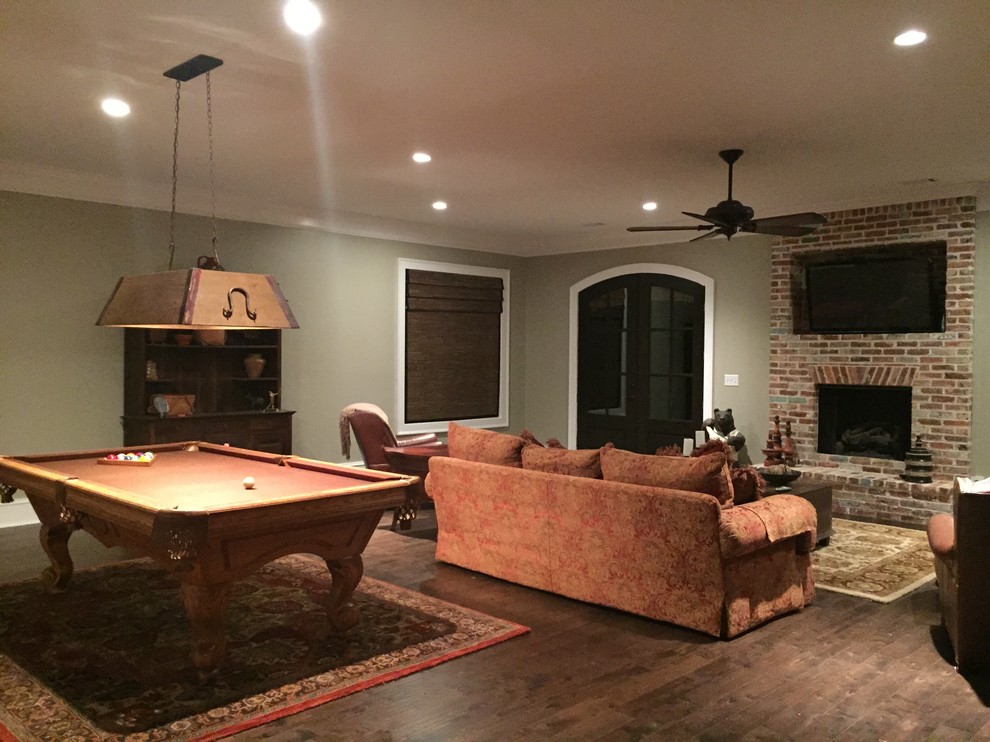 Example of a large classic underground dark wood floor basement design in Atlanta with beige walls, a standard fireplace and a brick fireplace