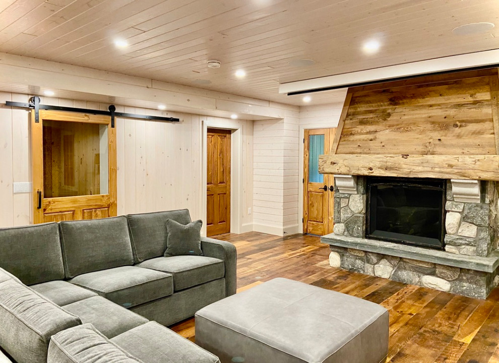 Photo of a medium sized classic walk-out basement in Toronto with a game room, white walls, medium hardwood flooring, a standard fireplace, a stone fireplace surround, brown floors, a timber clad ceiling and tongue and groove walls.