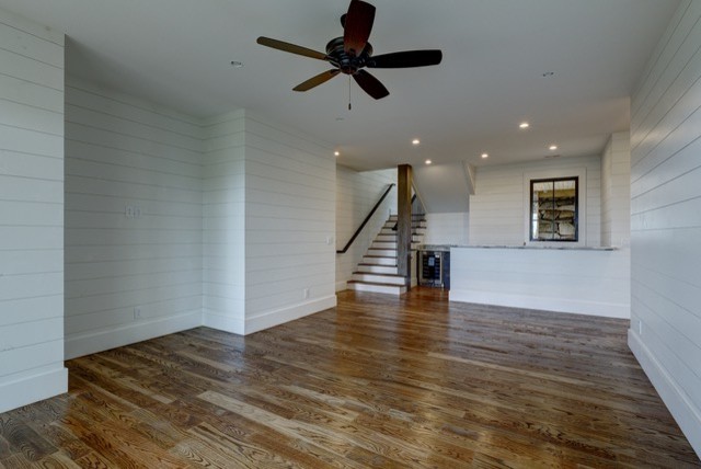 Foto de sótano con puerta rústico grande sin chimenea con paredes blancas, suelo de madera en tonos medios y suelo marrón