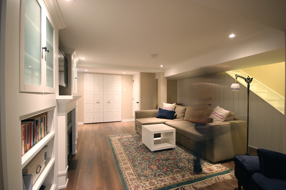 Design ideas for a medium sized traditional fully buried basement in Ottawa with beige walls, a standard fireplace, a brick fireplace surround, brown floors and dark hardwood flooring.