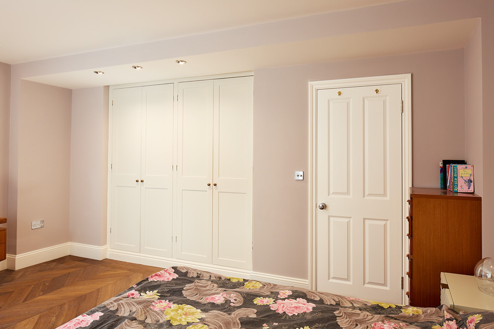 Exempel på en liten modern källare utan ingång, med rosa väggar, ljust trägolv och brunt golv
