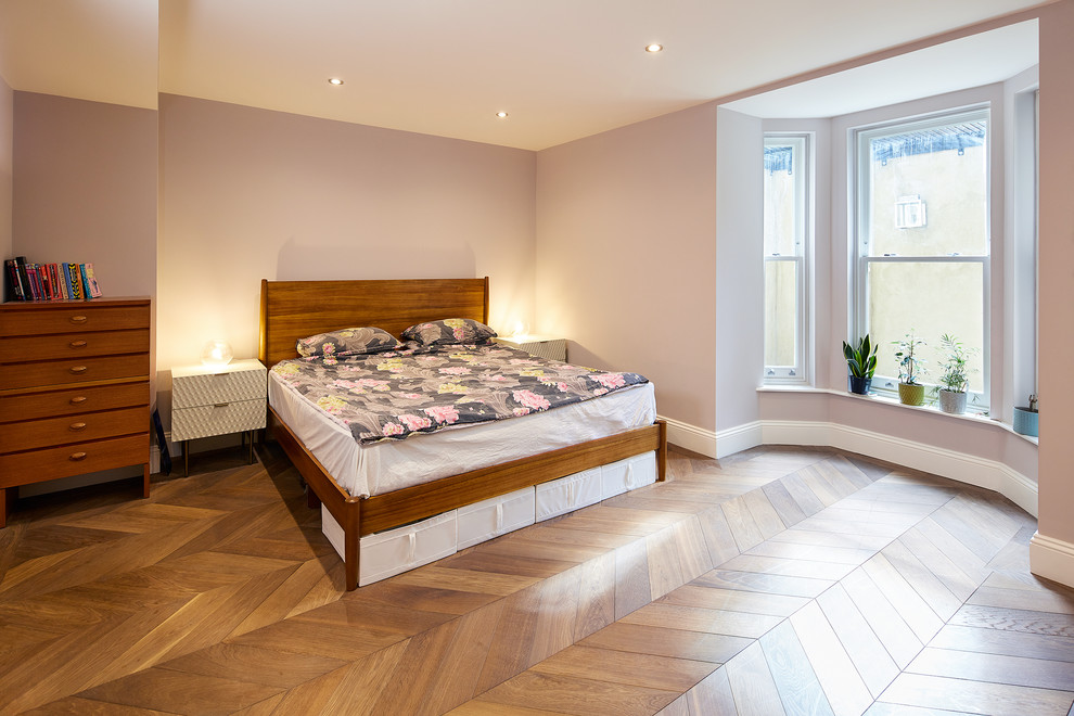 Immagine di una piccola camera da letto contemporanea con pareti rosa, parquet chiaro, nessun camino e pavimento marrone