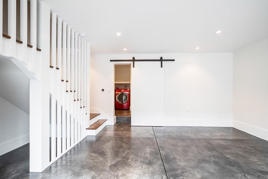 Ejemplo de sótano con puerta moderno con paredes blancas, suelo de cemento y suelo gris