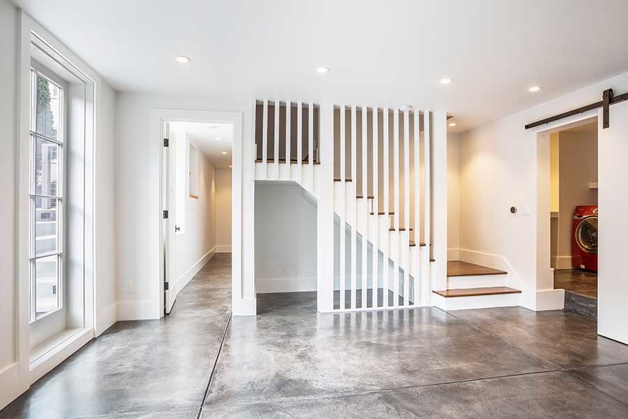 Imagen de sótano con puerta minimalista con paredes blancas, suelo de cemento y suelo gris