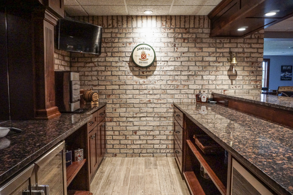 Foto di una piccola taverna rustica con sbocco, angolo bar, pareti bianche, parquet chiaro, camino bifacciale, cornice del camino in mattoni, pavimento grigio e pareti in mattoni