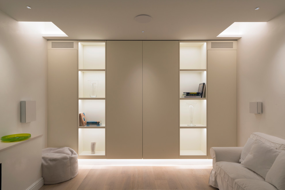 Photo of a medium sized contemporary basement in London with white walls and light hardwood flooring.