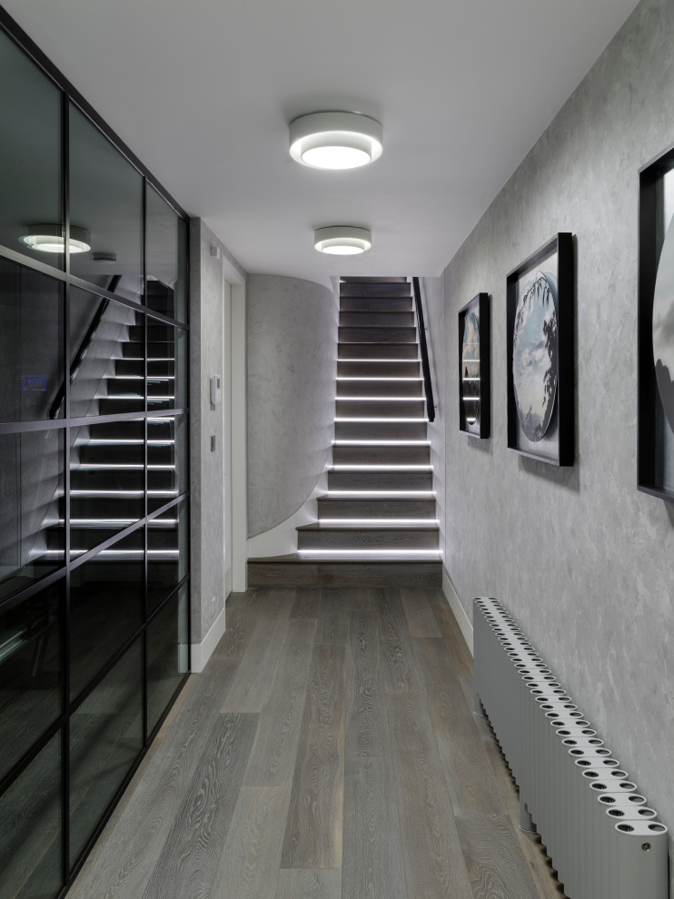 Basement - large contemporary underground medium tone wood floor and gray floor basement idea in London with gray walls