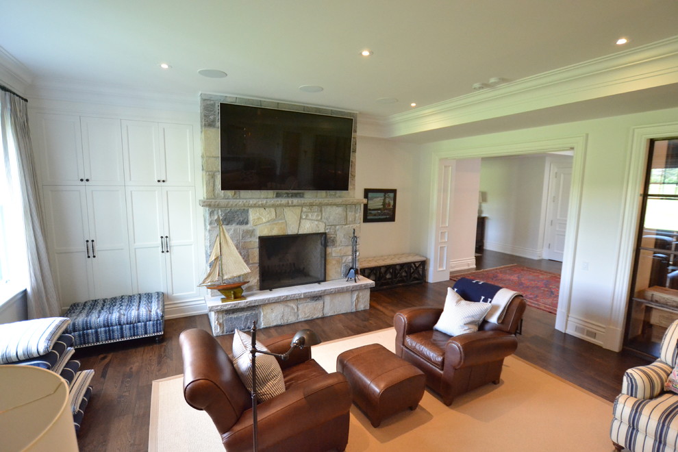 This is an example of a classic walk-out basement in Toronto with white walls, dark hardwood flooring, a wood burning stove, a stone fireplace surround and brown floors.