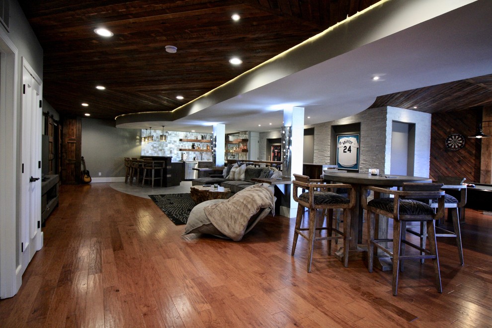 Basement - large rustic walk-out dark wood floor basement idea in St Louis with gray walls, a standard fireplace and a brick fireplace