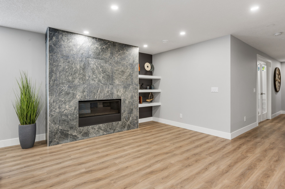 Foto på en mellanstor funkis källare utan fönster, med en hemmabar, grå väggar, vinylgolv, en standard öppen spis, en spiselkrans i trä och brunt golv