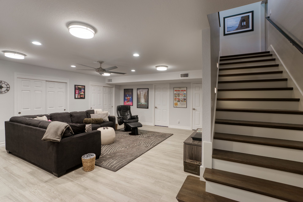 Photo of a medium sized contemporary look-out basement in Other with white walls, light hardwood flooring and beige floors.