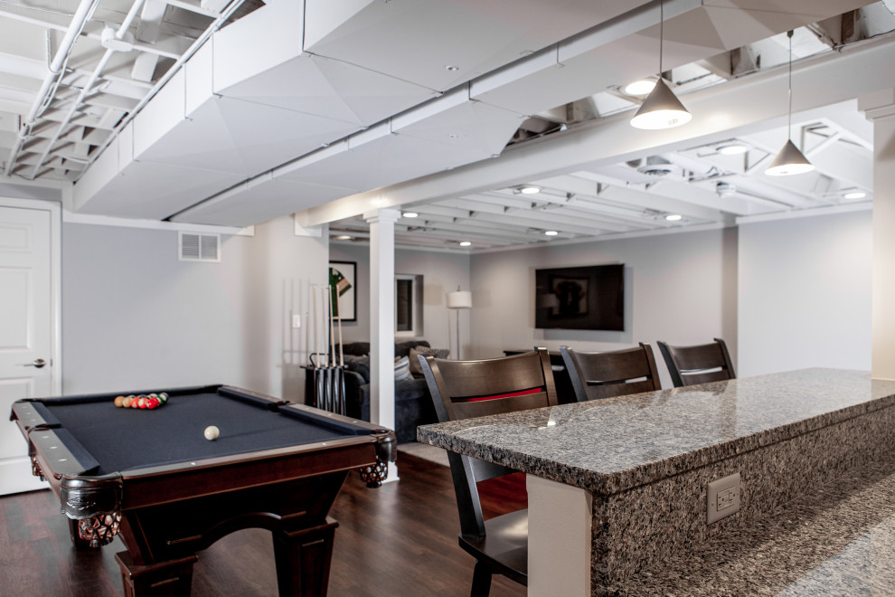 Large transitional underground vinyl floor, brown floor and exposed beam basement game room photo in Chicago with gray walls