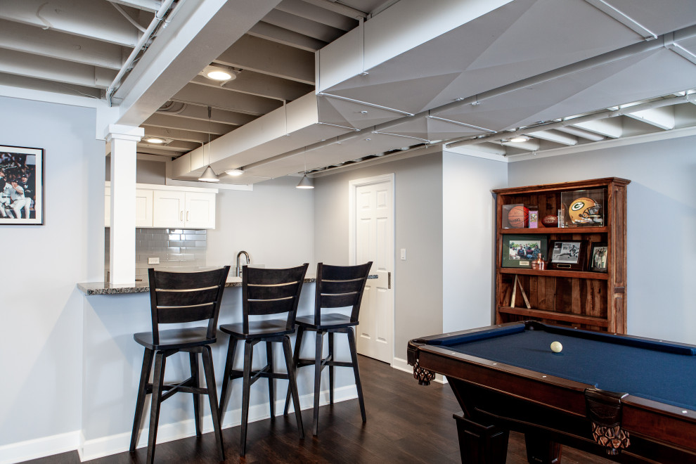 This is an example of a large classic fully buried basement in Chicago with a game room, grey walls, vinyl flooring, brown floors and exposed beams.