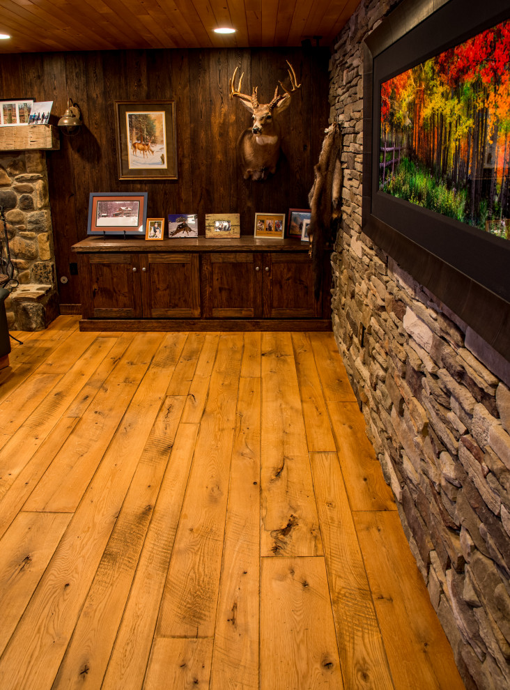 This is an example of a rustic basement in Other with medium hardwood flooring, a standard fireplace and a stone fireplace surround.