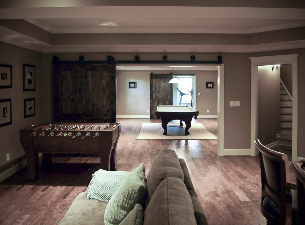 Ejemplo de sótano con puerta tradicional renovado grande con paredes grises y suelo de madera en tonos medios