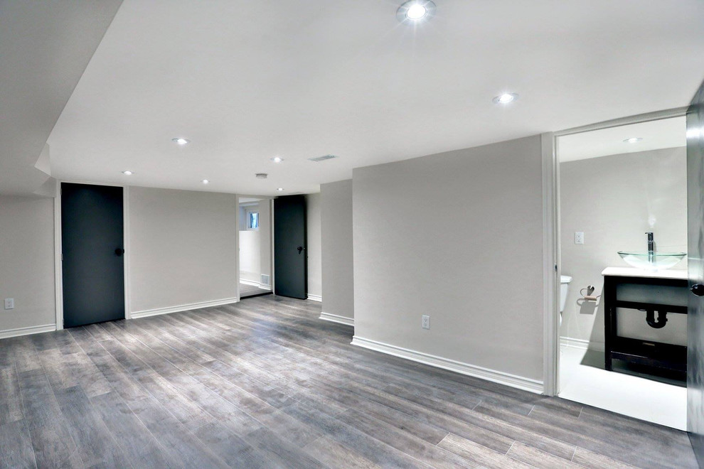 Photo of a large traditional basement in Toronto with grey walls, medium hardwood flooring, no fireplace and grey floors.