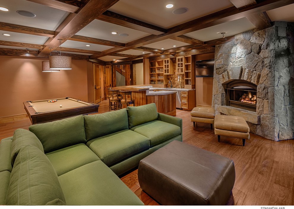 Inspiration for a large rustic underground medium tone wood floor basement remodel in Sacramento with beige walls, a standard fireplace and a stone fireplace
