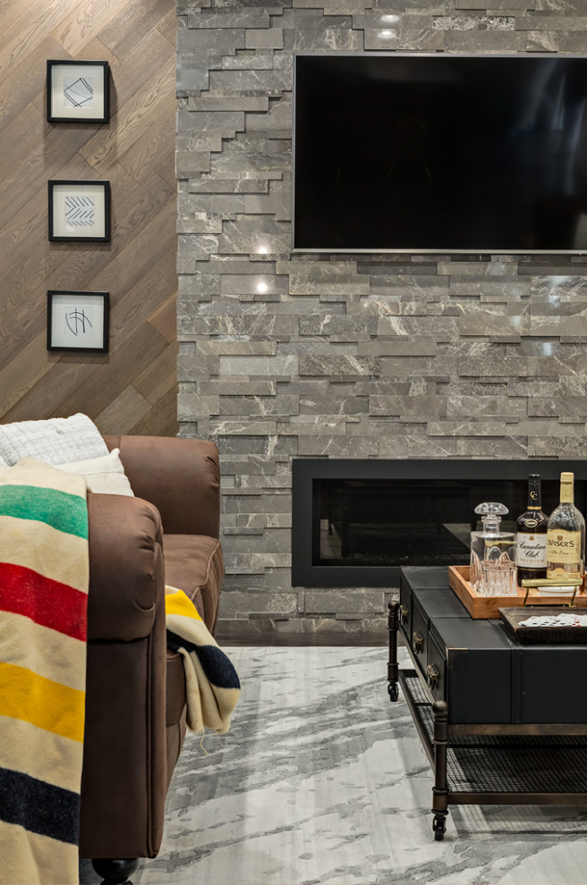 Idée de décoration pour un sous-sol design avec sol en béton ciré, une cheminée standard, un manteau de cheminée en pierre de parement et un sol gris.