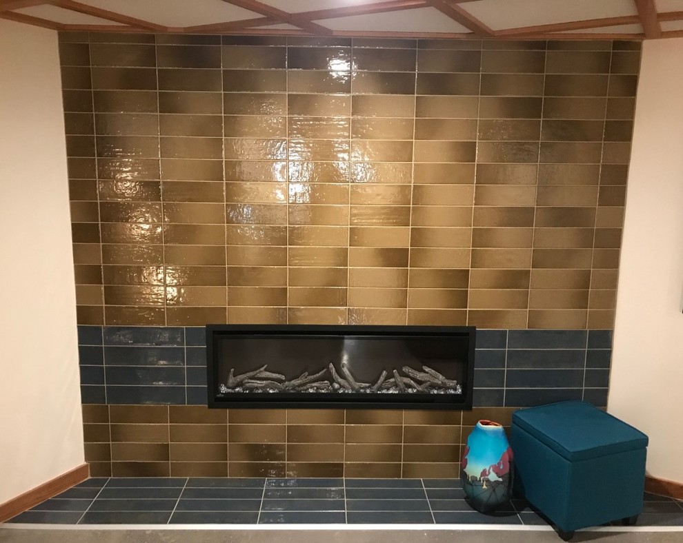 Стильный дизайн: большой подвал в стиле ретро с коричневыми стенами, полом из керамической плитки, стандартным камином, фасадом камина из плитки и синим полом - последний тренд