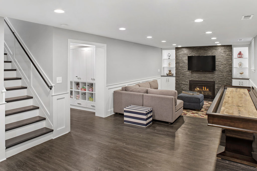 Inspiration for a huge transitional look-out vinyl floor and gray floor basement remodel in Columbus with gray walls, a standard fireplace and a stone fireplace