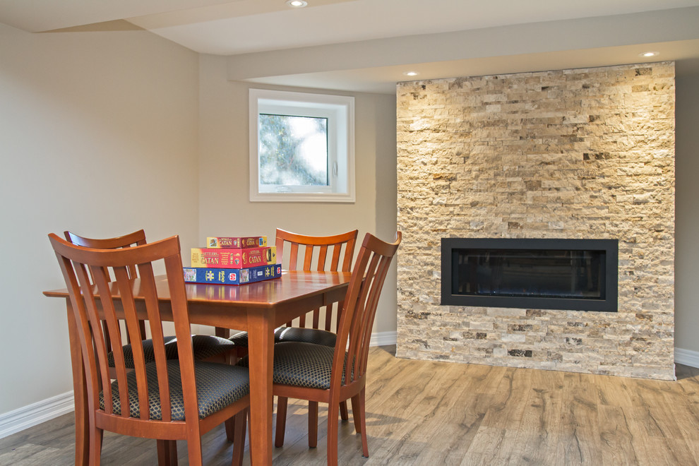 Large contemporary look-out basement in Toronto with grey walls, a standard fireplace and a stone fireplace surround.