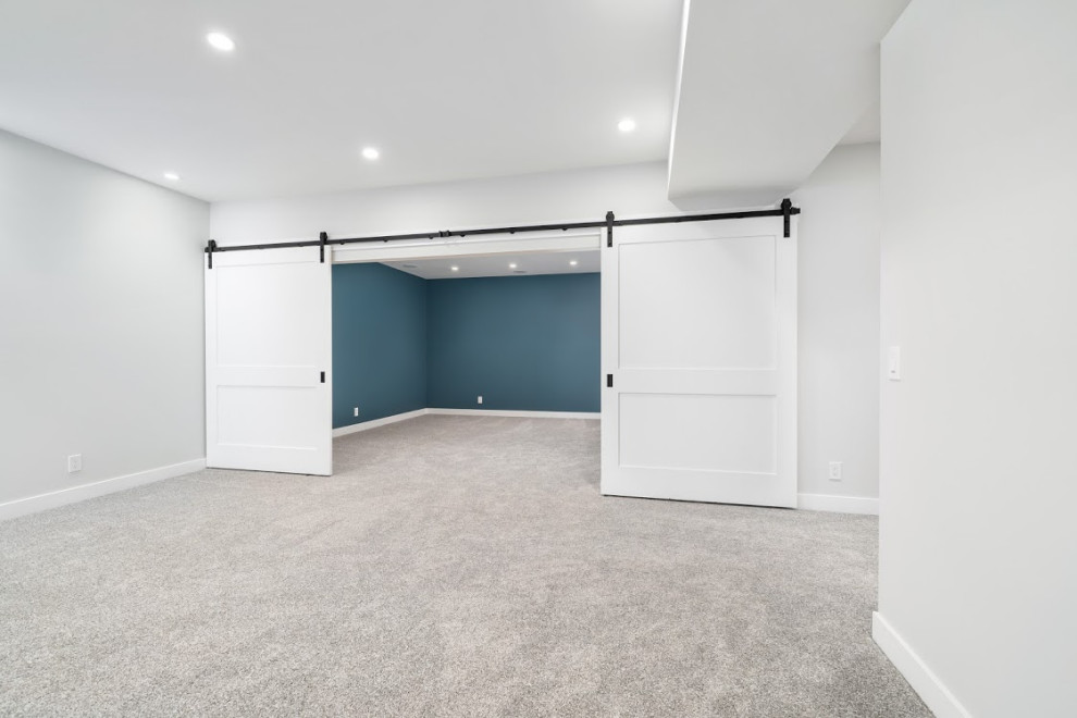 Cette photo montre un grand sous-sol nature avec salle de cinéma, un mur bleu, moquette et un sol gris.