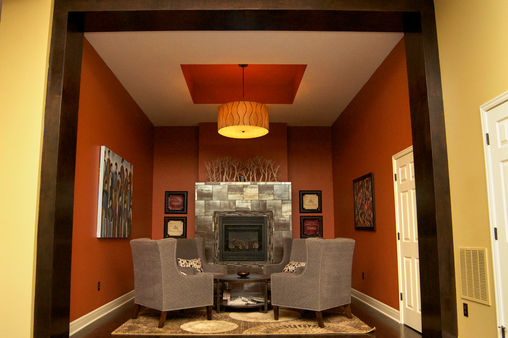 Réalisation d'un sous-sol minimaliste enterré et de taille moyenne avec un mur orange, parquet foncé, une cheminée standard, un manteau de cheminée en métal et un sol marron.