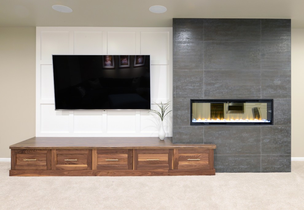 This is an example of a large modern basement in Other with grey walls, carpet, a two-sided fireplace, a wooden fireplace surround and beige floors.