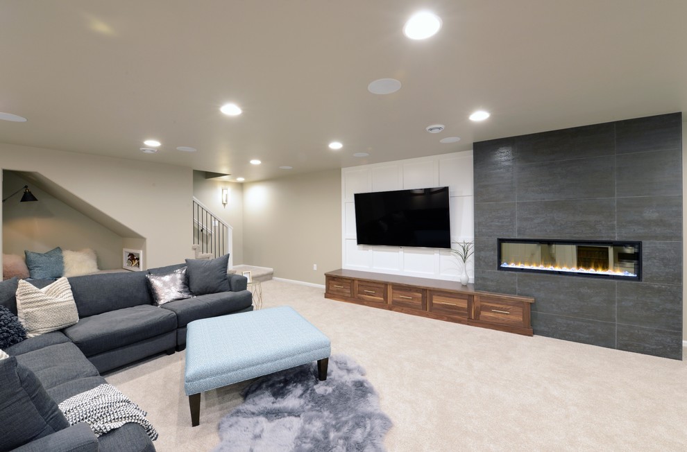 Idée de décoration pour un grand sous-sol minimaliste semi-enterré avec un mur gris, moquette, une cheminée double-face, un manteau de cheminée en bois et un sol beige.