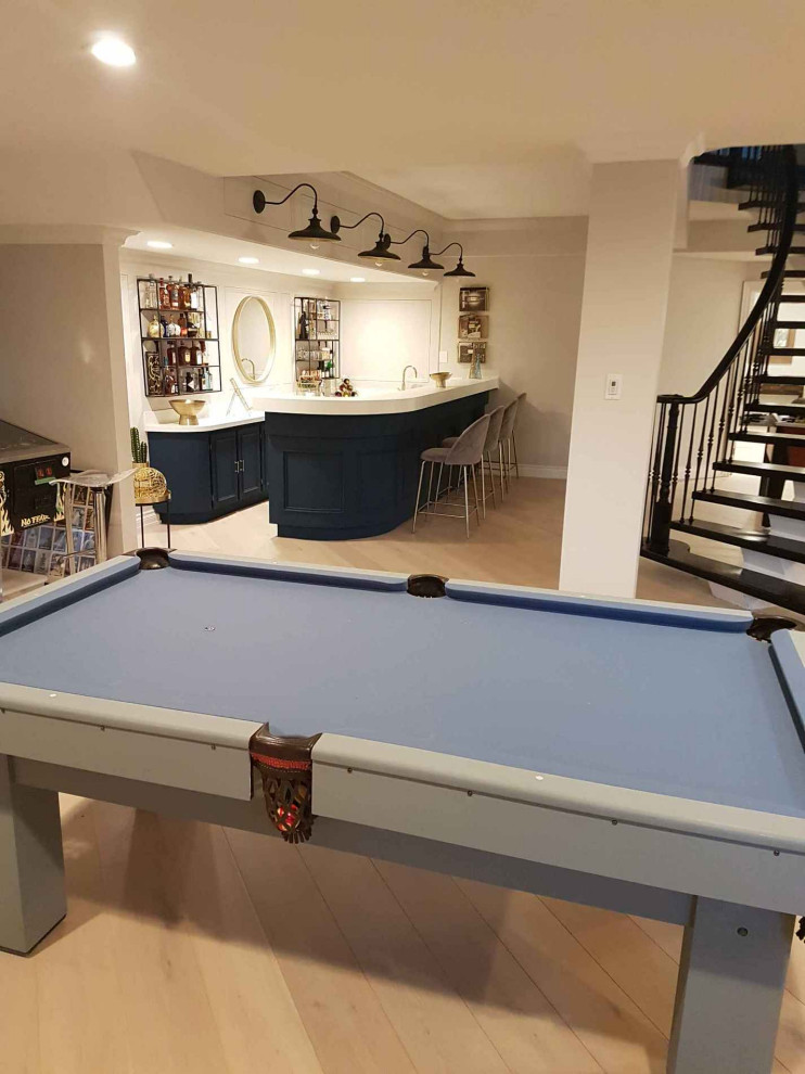 Large traditional fully buried basement in Toronto with a game room, white walls, light hardwood flooring and white floors.