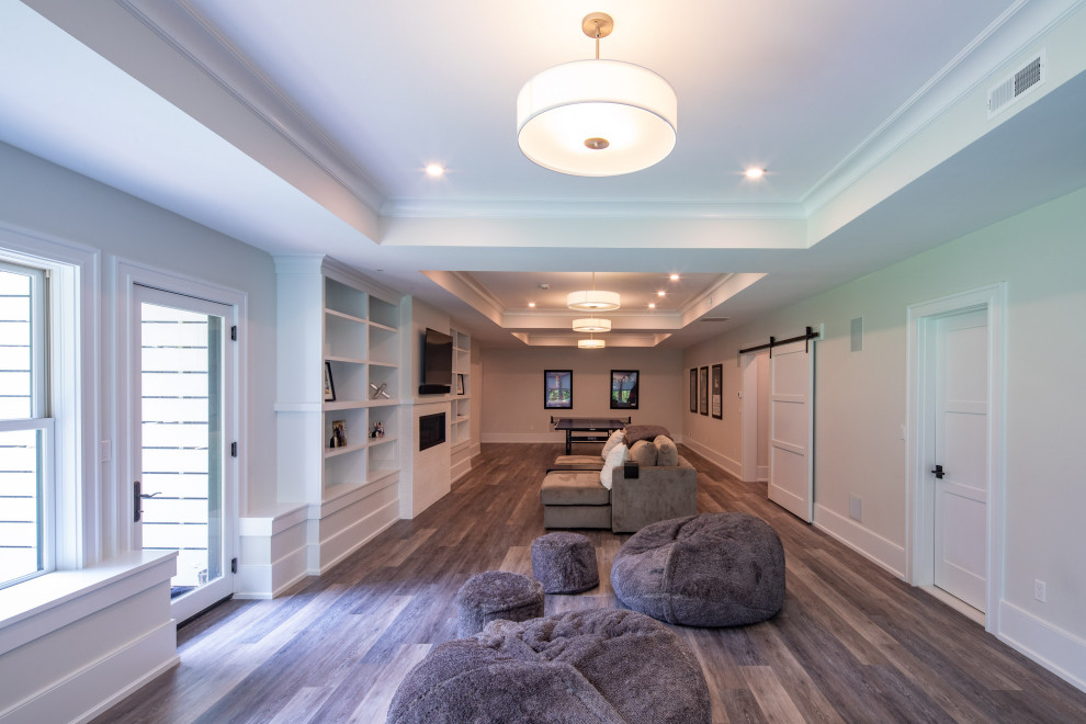 Large farmhouse walk-out medium tone wood floor and gray floor basement photo in Boston with white walls, a standard fireplace and a tile fireplace