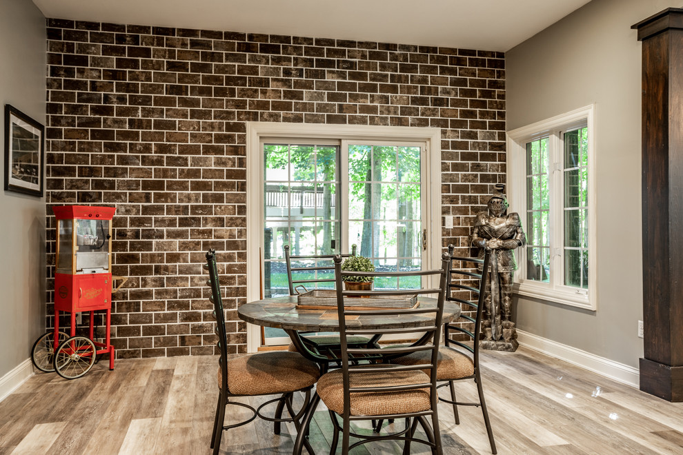 Cette image montre une grande salle à manger chalet avec un mur gris, un sol en vinyl, une cheminée standard, un manteau de cheminée en pierre et un sol marron.