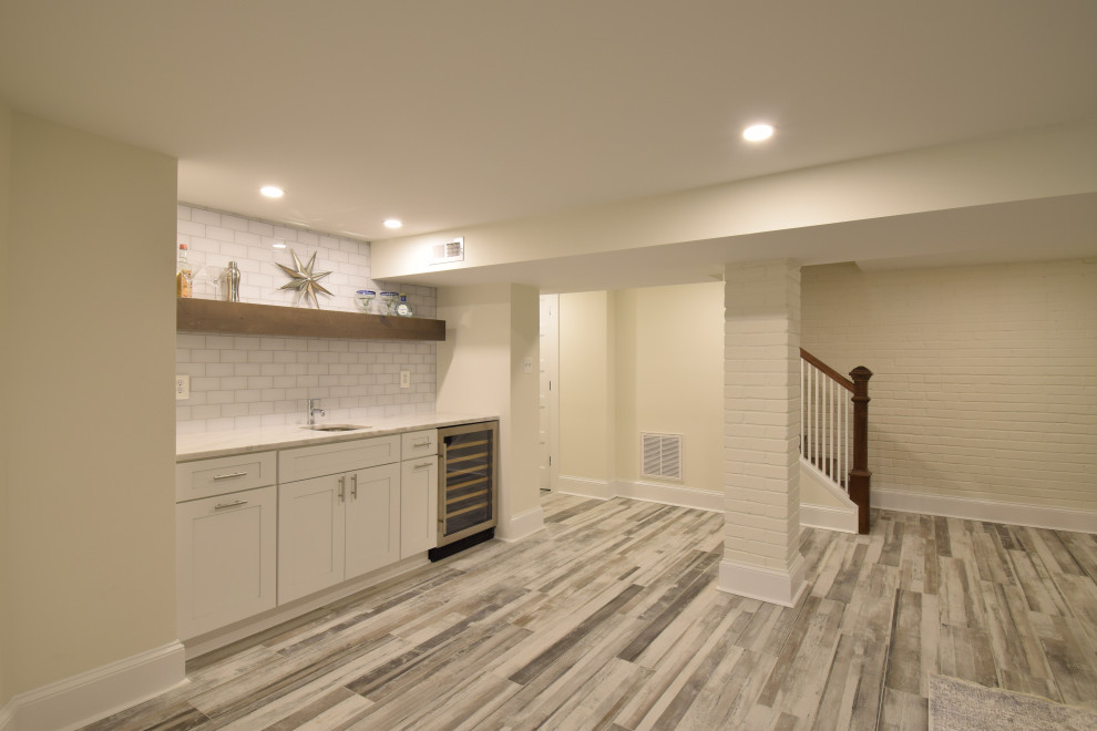 This is an example of a large classic walk-out basement in DC Metro with white walls, porcelain flooring and multi-coloured floors.
