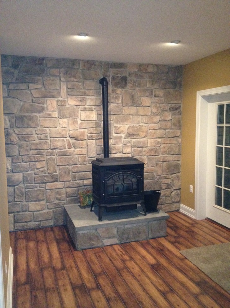 Example of a large classic walk-out dark wood floor basement design in Baltimore with beige walls and a wood stove