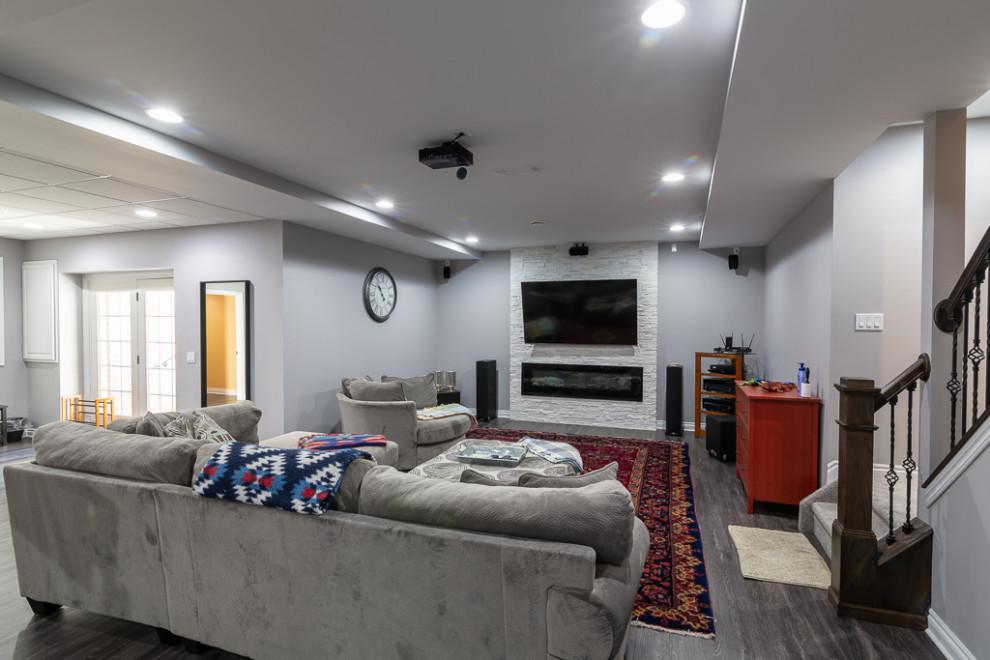 This is an example of a large classic walk-out basement in Chicago with grey walls, vinyl flooring, a ribbon fireplace, a stone fireplace surround and grey floors.