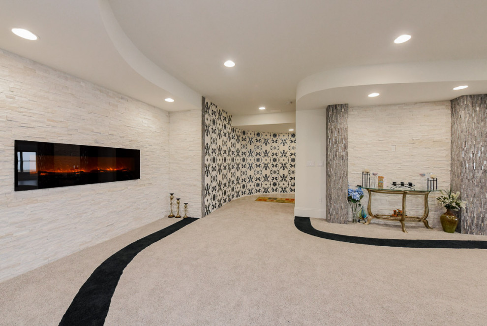 This is an example of a large walk-out basement in Chicago with white walls, carpet, a ribbon fireplace, a stone fireplace surround and beige floors.