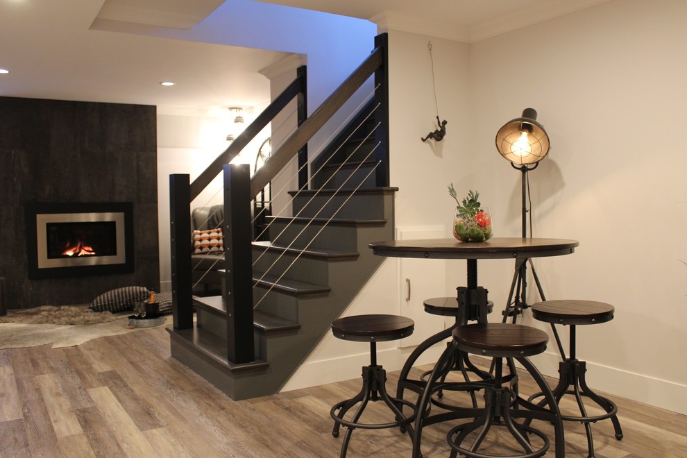 Inspiration for a large modern look-out basement in Calgary with grey walls, laminate floors, a standard fireplace, a tiled fireplace surround and beige floors.