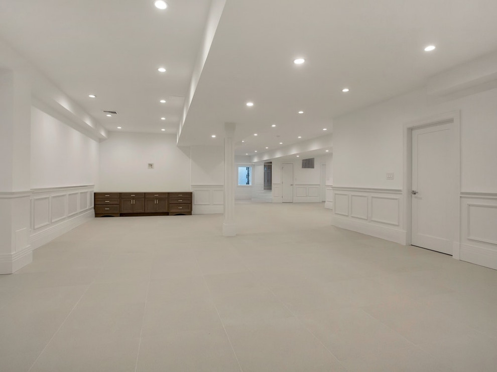 Exemple d'un très grand sous-sol tendance donnant sur l'extérieur avec un mur blanc, un sol en carrelage de céramique et un sol beige.