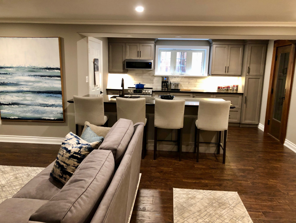 Photo of a medium sized contemporary walk-out basement in Toronto with grey walls, vinyl flooring, a standard fireplace, a tiled fireplace surround and brown floors.