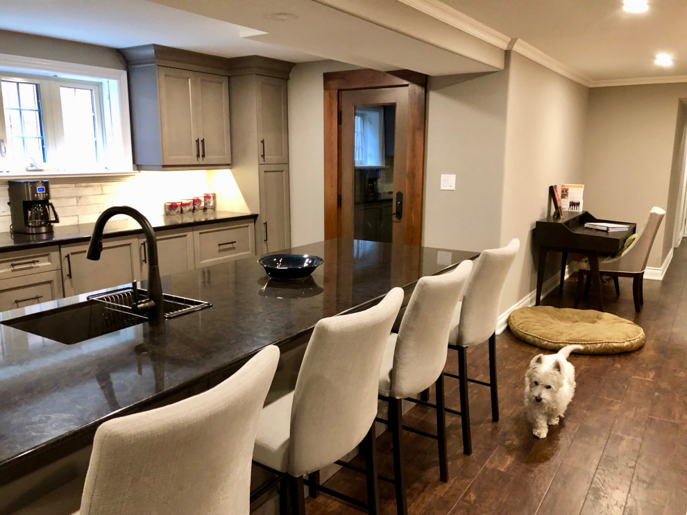 This is an example of a medium sized contemporary walk-out basement in Toronto with grey walls, vinyl flooring, a standard fireplace, a tiled fireplace surround and brown floors.
