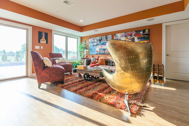 Example of a large eclectic light wood floor and beige floor basement design in Louisville with orange walls