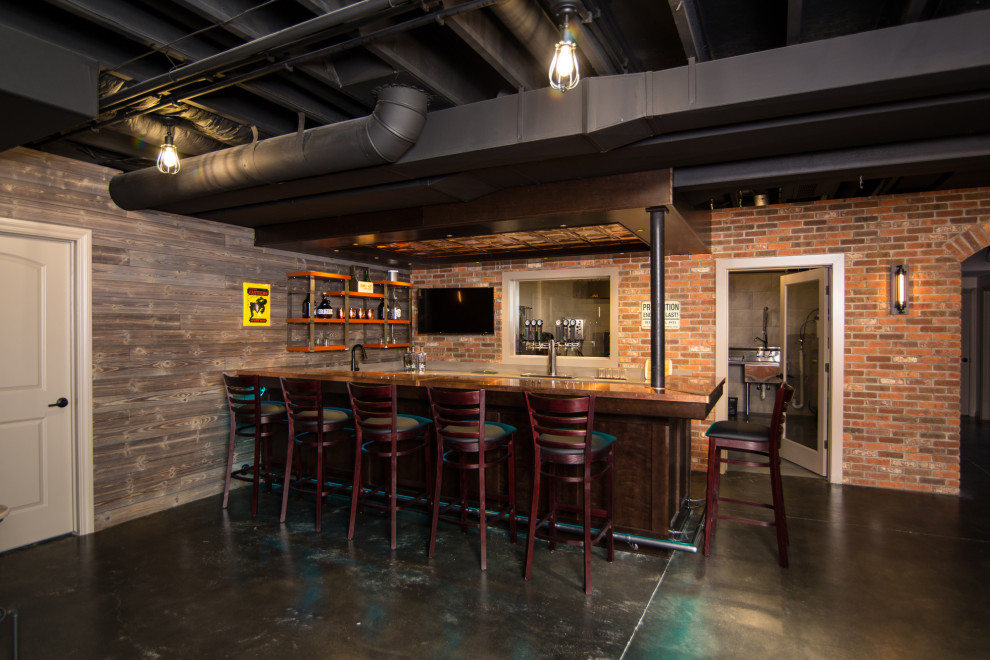 This is an example of a large industrial basement in Detroit with a home bar, concrete flooring and exposed beams.