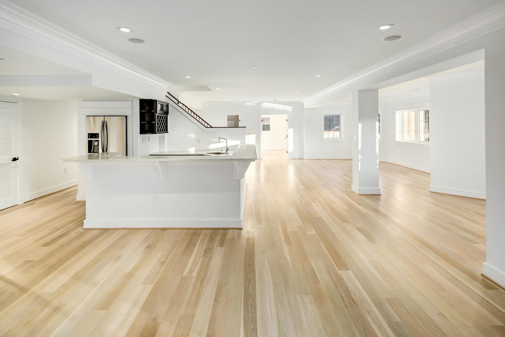 Inspiration for a large modern walk-out basement in DC Metro with white walls, light hardwood flooring, a ribbon fireplace, a stone fireplace surround and beige floors.