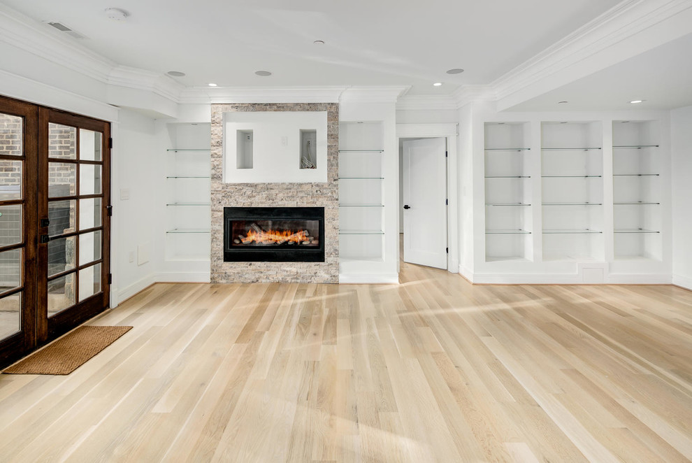 Design ideas for a large modern walk-out basement in DC Metro with white walls, light hardwood flooring, a ribbon fireplace, a stone fireplace surround and beige floors.