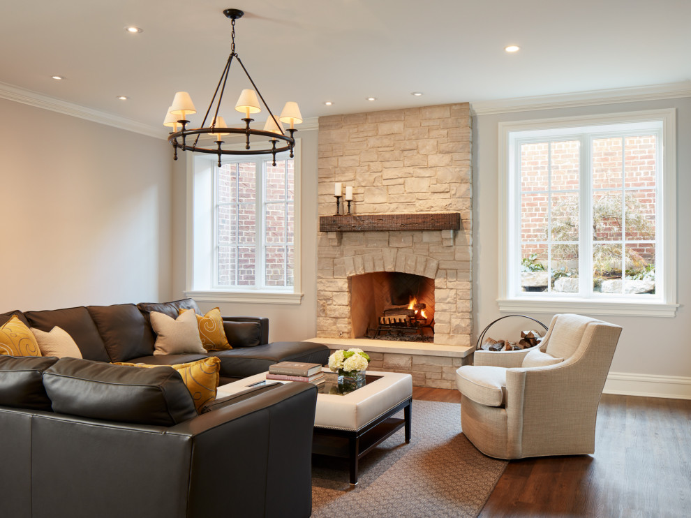 This is an example of a classic look-out basement in Chicago with grey walls, vinyl flooring, a standard fireplace, a stone fireplace surround and brown floors.